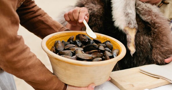 pilgrim serves mussels to seated guest