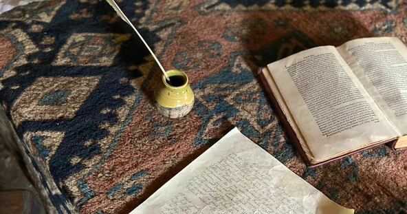 Book, parchment, quill, and ink on table