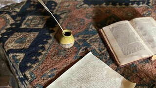 Book, parchment, quill, and ink on table