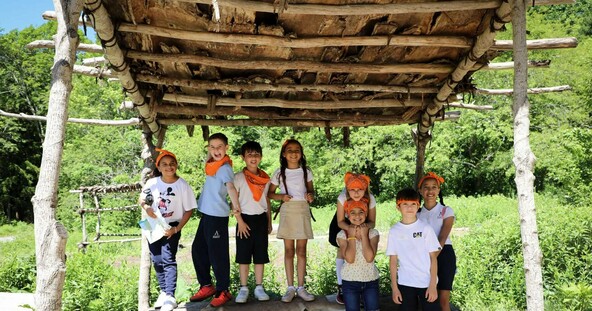 Multiple school children under outdoor arbor on Historic Patuxet Homesite