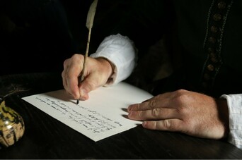A man writes a document with a quill pen