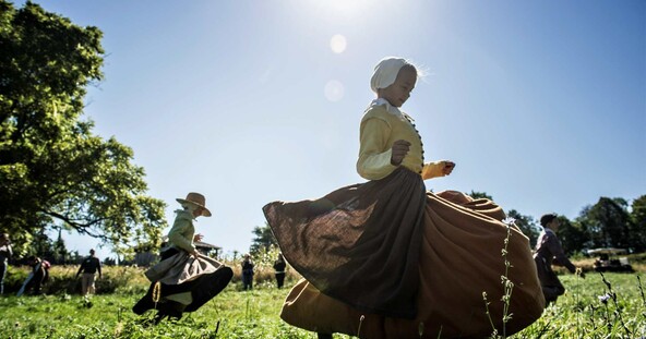 children dressed as pilgrims run in a field