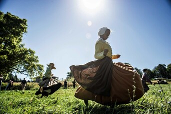 children dressed as pilgrims run in a field