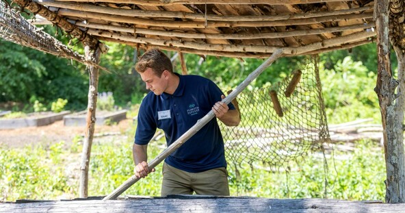 museum educator works on making a mishoon in an outdoor setting