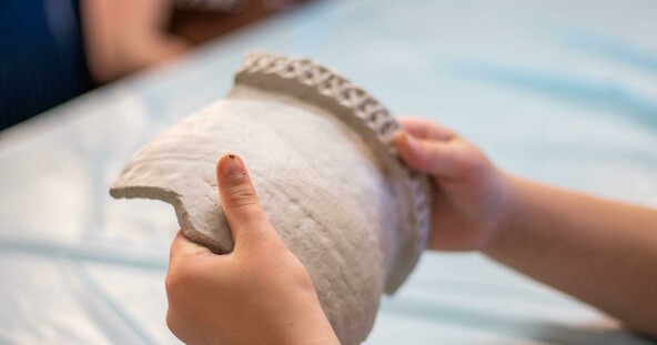 Child holds a piece of tan pottery