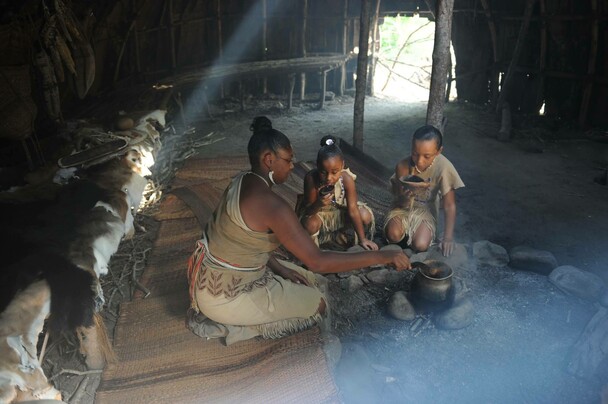 A woman serves two children nasaump in a wetu
