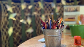 table with craft supplies including a silver bucket filled with colored pencils