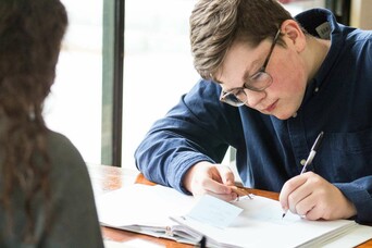 Student takes notes at a desk