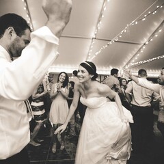 Bride and groom dance with wedding guests under a tent