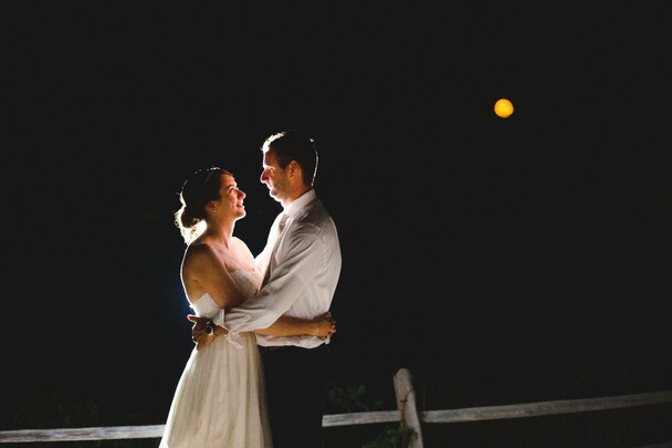 Bride and groom embrace under a full moon