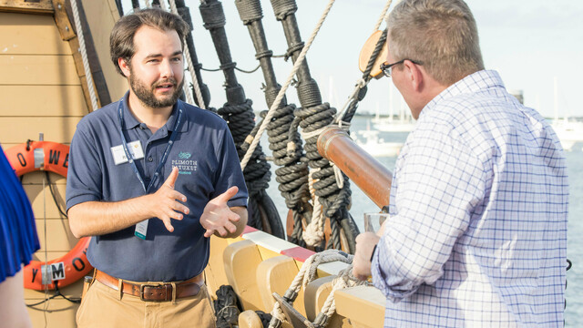 Mayflower II crew member in conversation with guest aboard the ship.