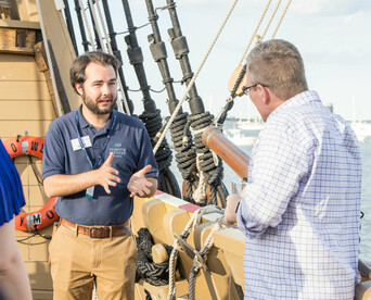 Mayflower II crew member in conversation with guest aboard the ship.