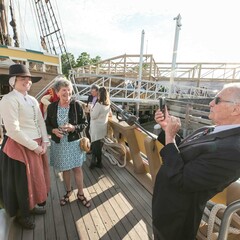 Guest poses for with a female pilgrim aboard Mayflower II.