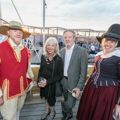 Chris Cooper and Marianne Leone pose with a female pilgrim and male pilgrim aboard Mayflower II.