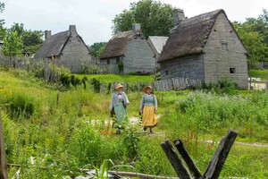 Two pilgrim women walking in back of houses