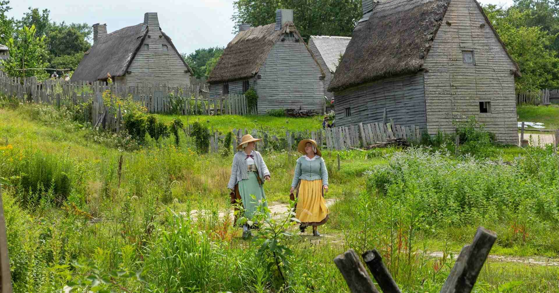 Two pilgrim women walking in back of houses