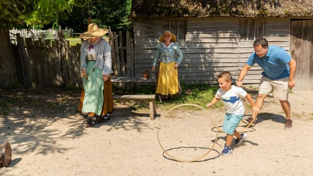 Father and son spin hoops with Pilgrims in English Village