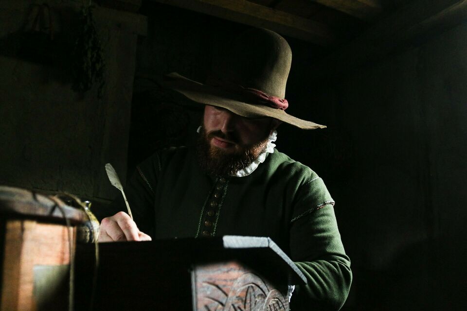 Man writes with quill pen at desk