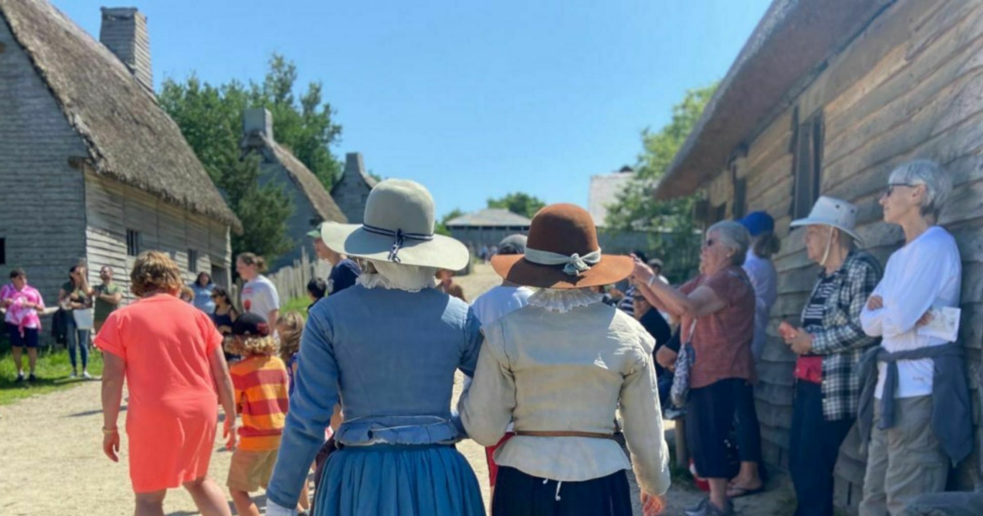 Two pilgrims walk through crowd while linking arms