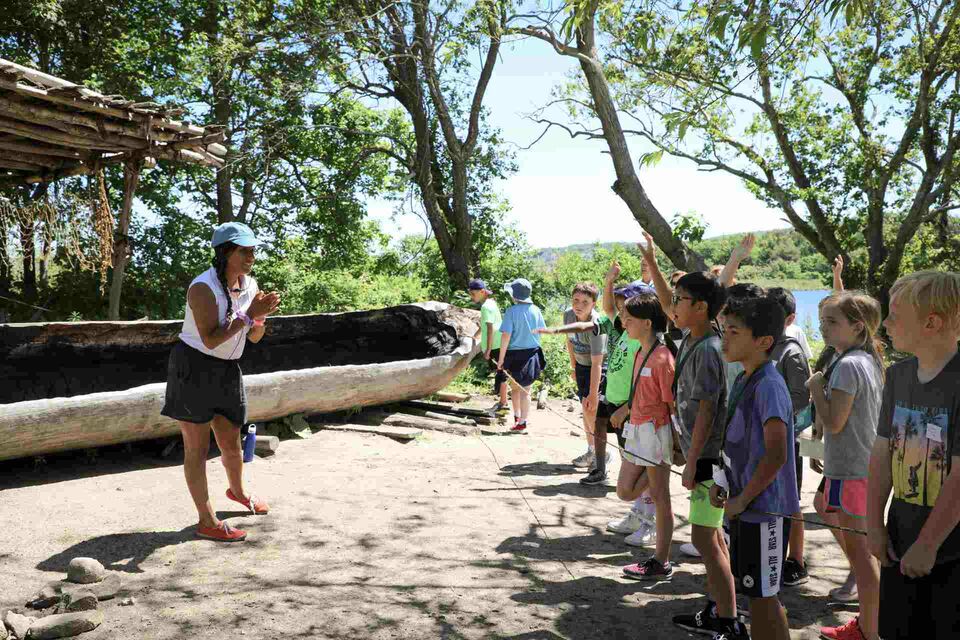 Museum educator teaches group of children near mishoon