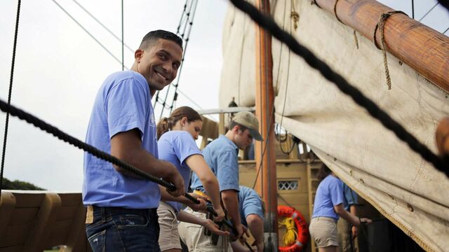 Four people work together to pull rope on ship