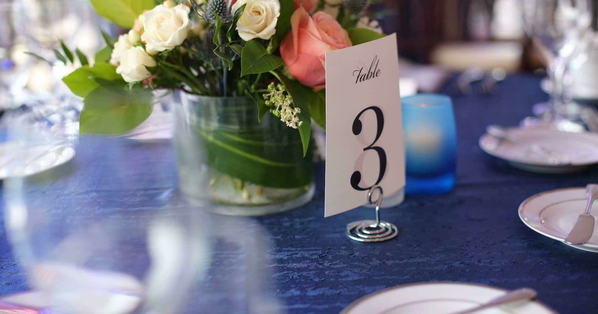 table set for a formal event with a floral centerpiece and number three on a white card
