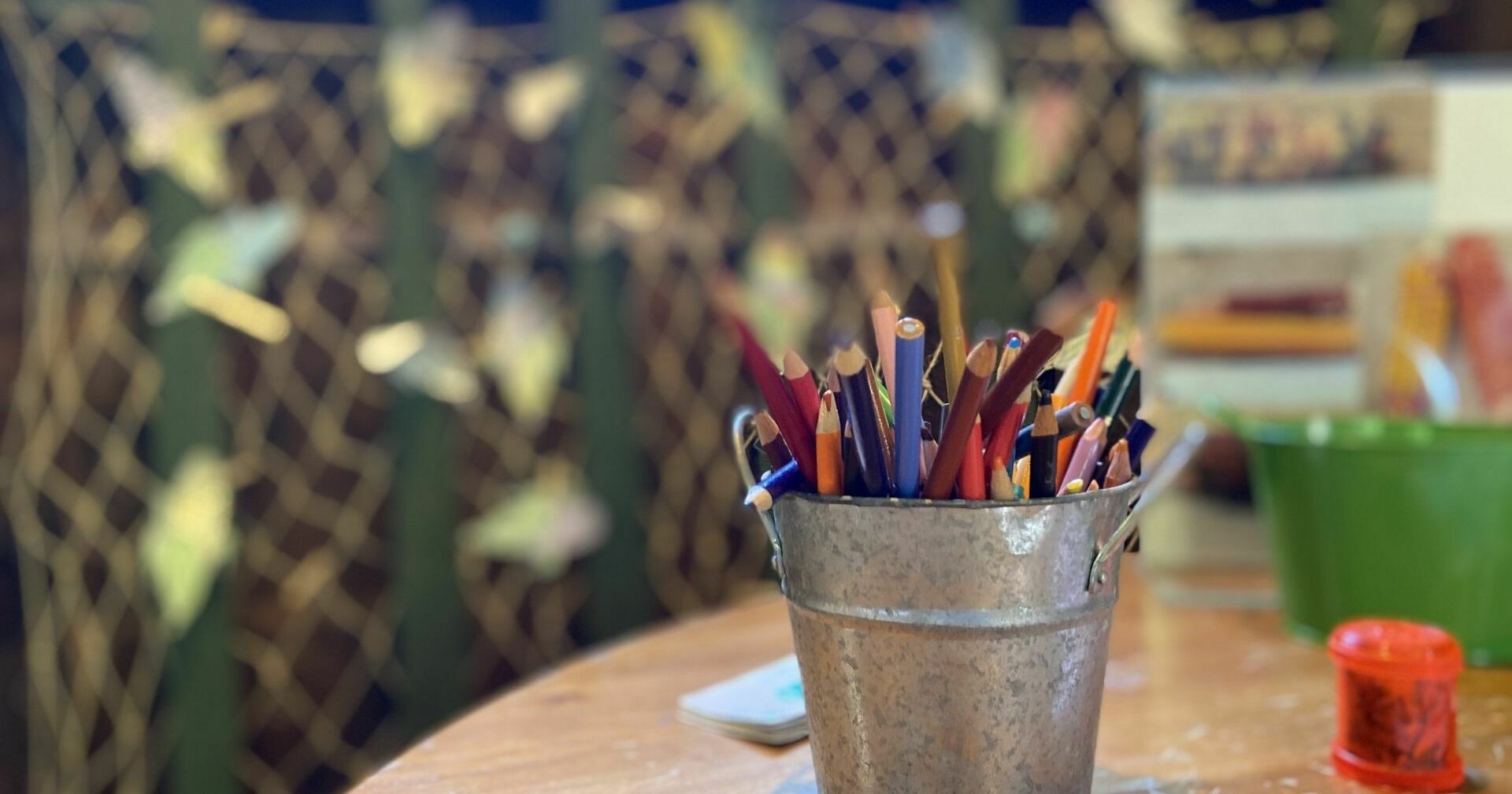 table with craft supplies including a silver bucket filled with colored pencils